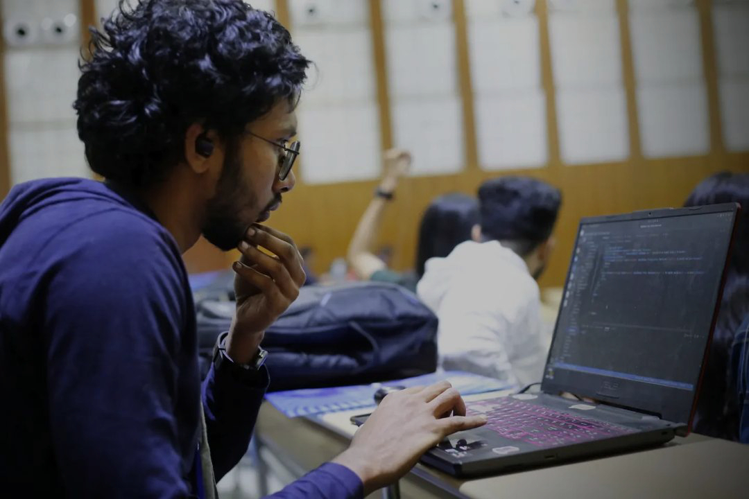 Ayush building on a laptop alongside other participants at a hackathon